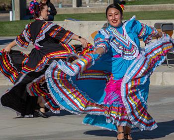 两名身着传统拉丁服装的女舞者在户外活动中跳舞